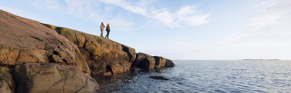 Kaksi ihmistä kalliolla tyynen meren äärellä