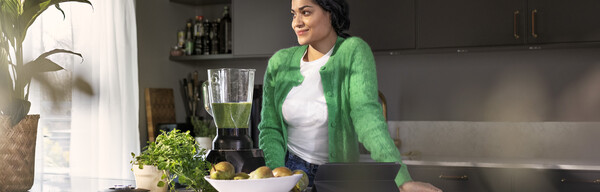 Nainen vihreässä käyttää Fortumin sähköä kotona